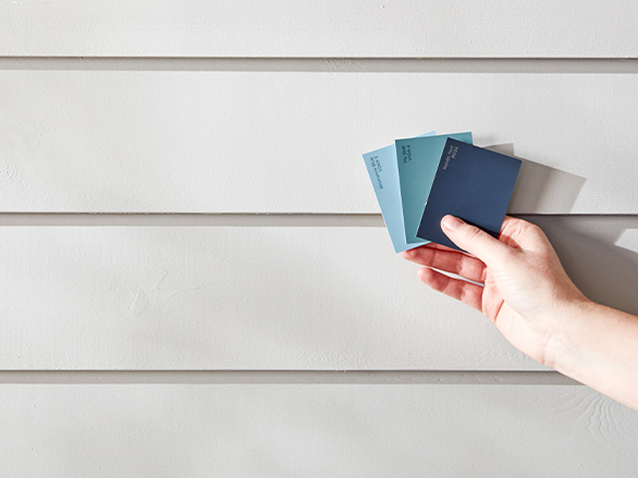 Hand holding three fanned color chips, in shades of blue