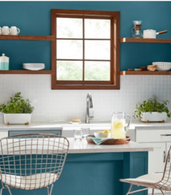 Kitchen with Sky Space counter and wall, white cabinets, gray countertop and wood trim and shelves.