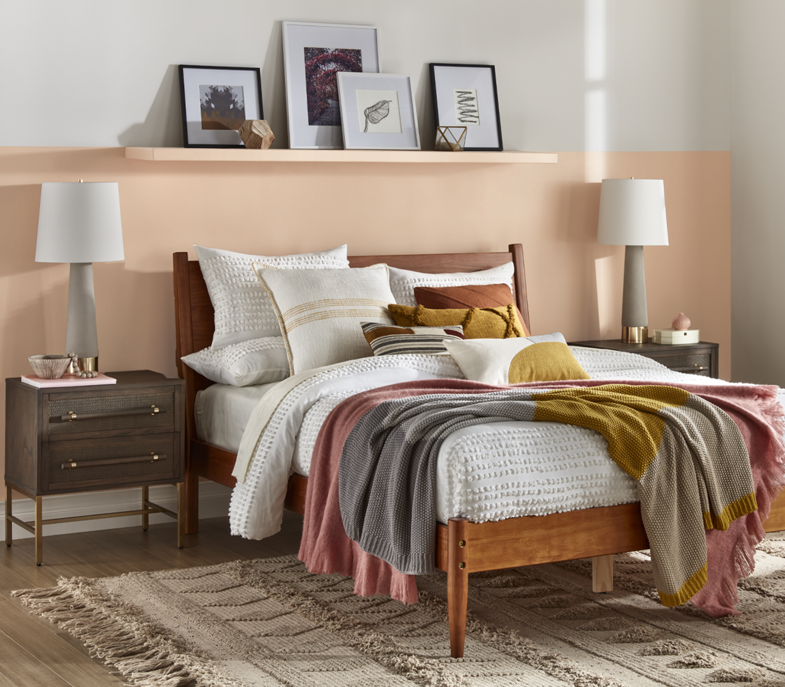 Pillow-covered bed against sandy neutral half wall accent color with matching shelf and modern side-table lamps.