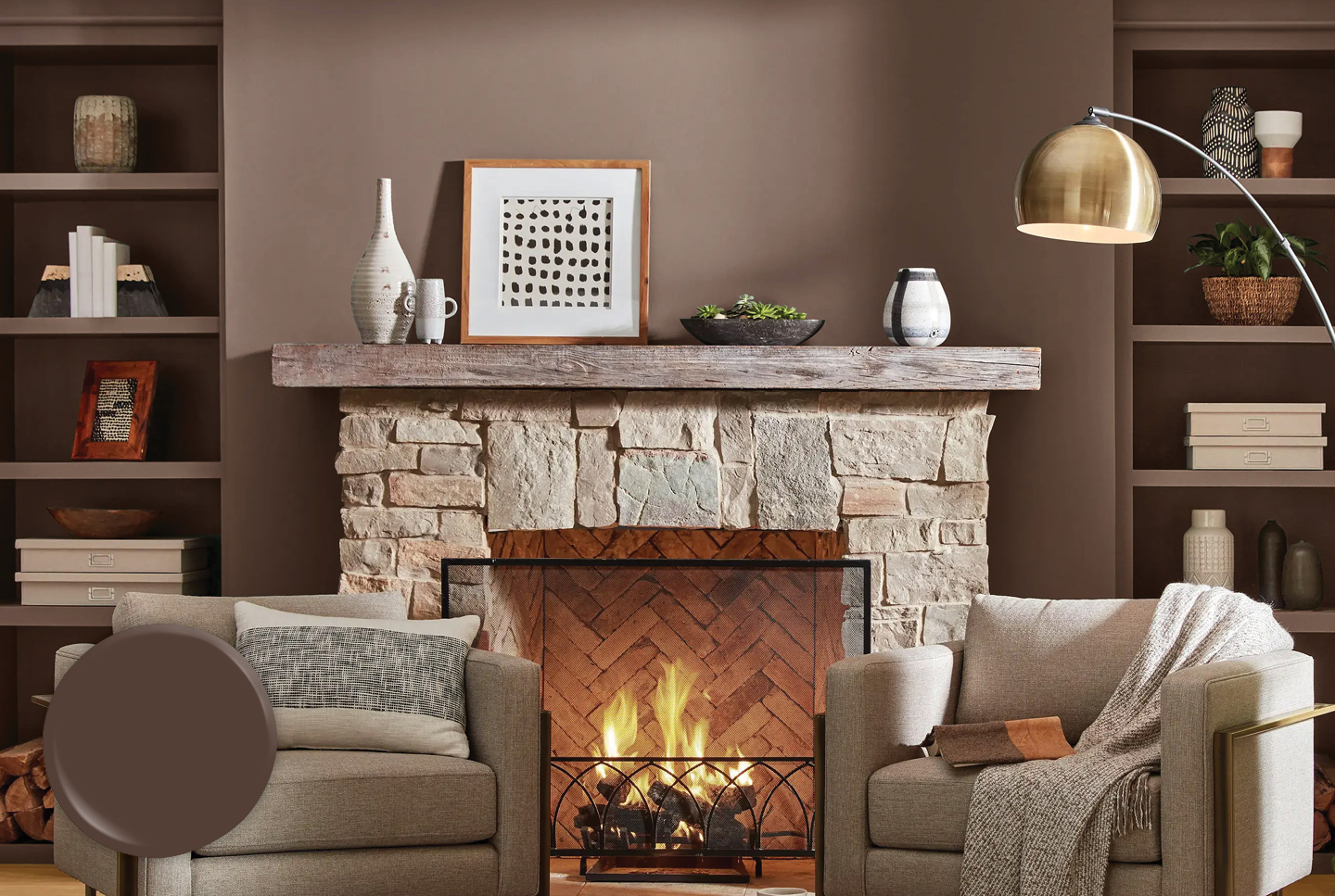 Stone fireplace with wood mantel against a Cabin Plank wall. A soft blanket is strewn on one of two upholstered chairs. 