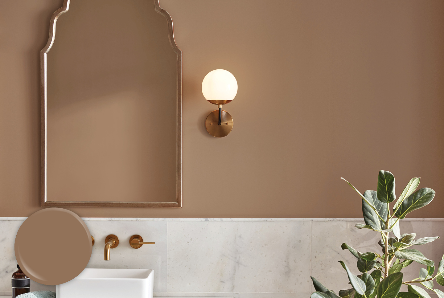 Bathroom with half wall of marble. Top half painted in Dark Toast. Gold-toned fixtures and white sink.